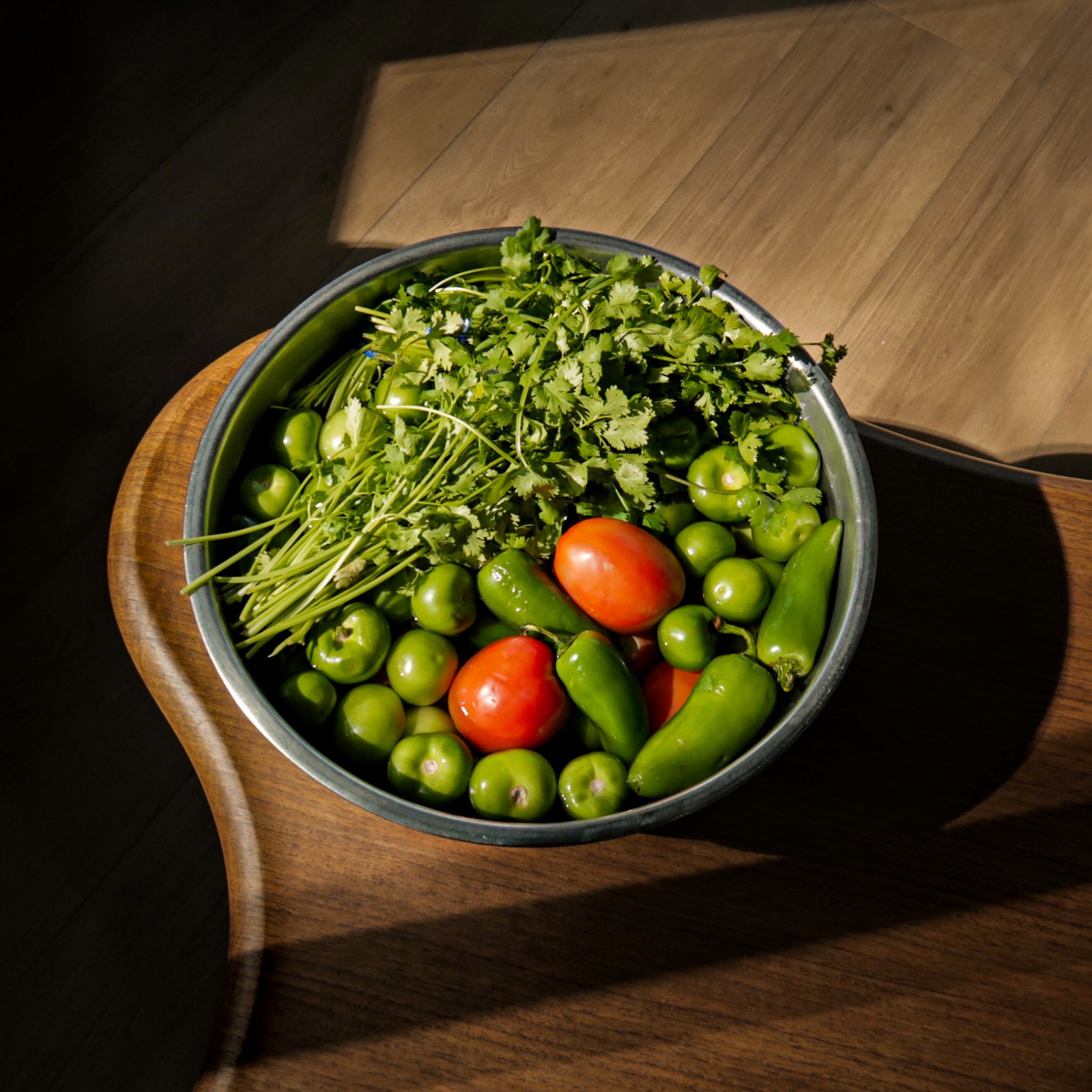A bowl of fresh tomatillos, tomatoes, jalapeños and cilantro